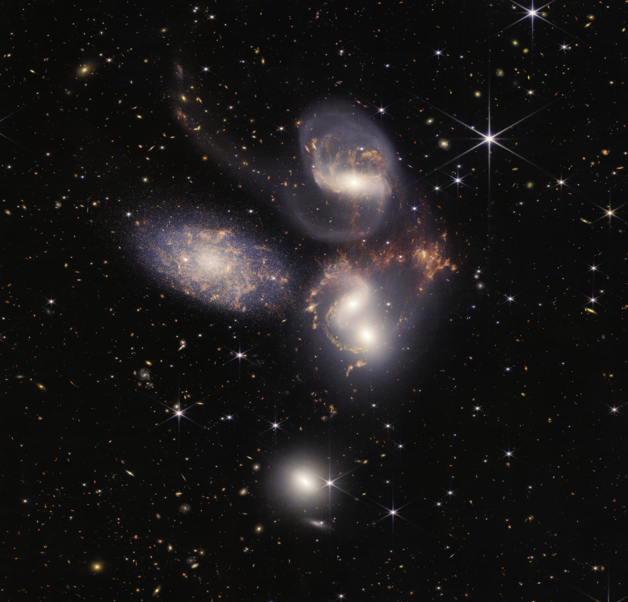 Stephan’s Quintet is a set of five galaxies. The leftmost one is actually in the foreground, and the other 4 are very close together. So close that they are what we call “interacting” – they are pulling on each other, with the two center right actually merging into one galaxy. These interactions cause lots of stars to be formed, as the gas they are made out of is churned around.